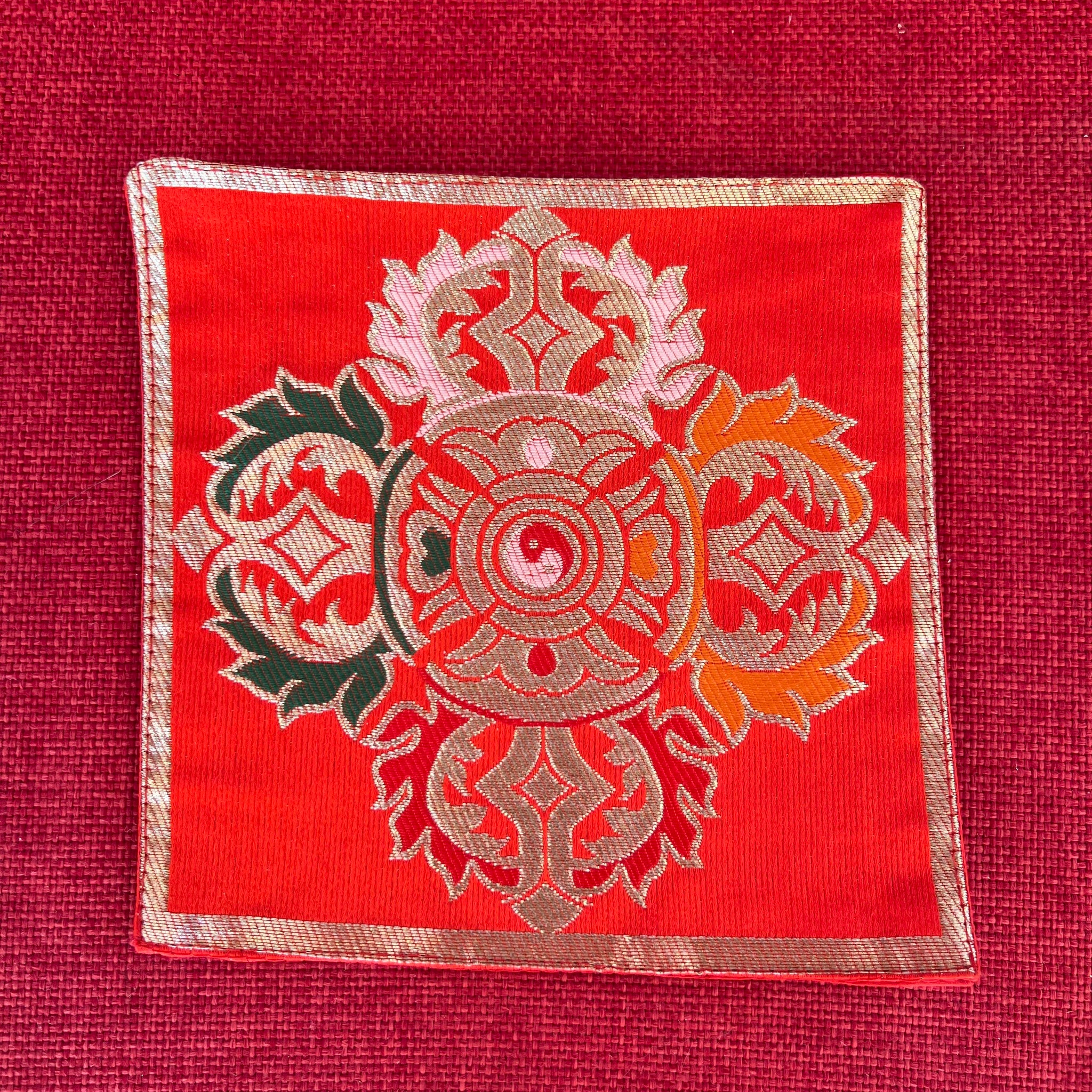 Red brocade Bell and Dorje mat with double dorje in centre