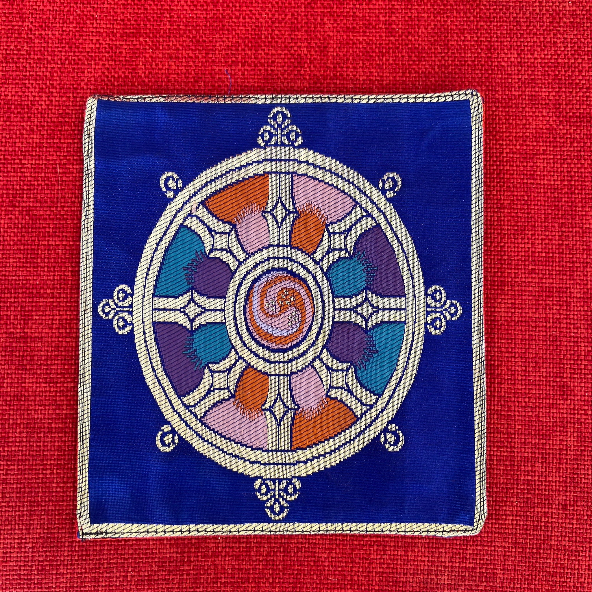 Blue brocade Bell and Dorje mat with dharma wheel symbol in centre