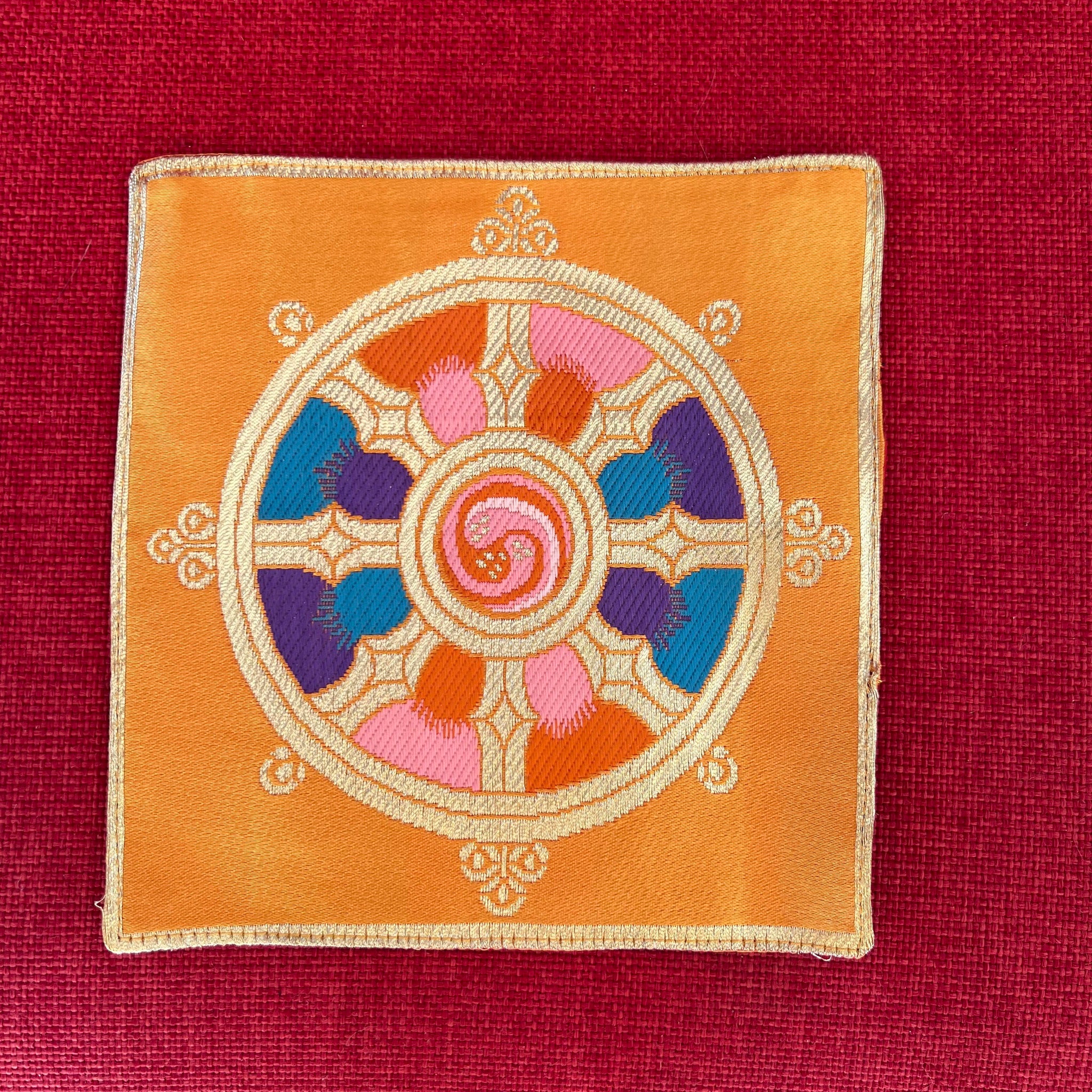 Yellow brocade Bell and Dorje mat with dharma wheel symbol in centre