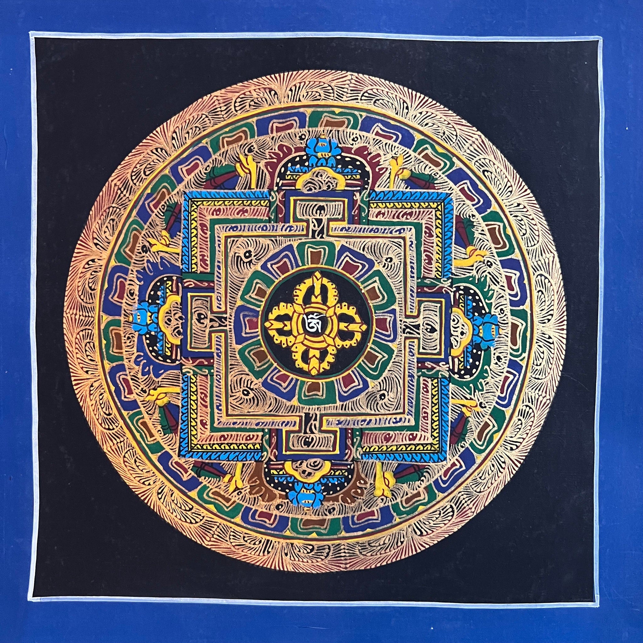 26cm Square Mandala Painting with the Tibetan Om symbol and Double Dorje inside a symbolic palace and a black background with blue border