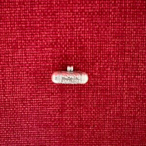 2.3cm long silver horizontal cylinder locket embossed with Tibetan Om, Buddha Eyes and the dorje symbol and contains scroll with Om Mani Padme Hung mantras inside